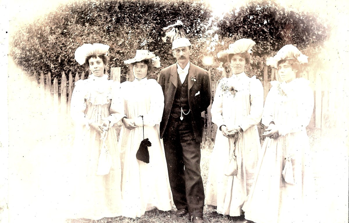Faded early 1900s photograph of Clara Jane Holt standing with Alf Briant and family members in white dresses